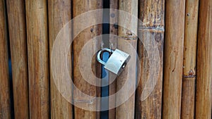 Brown bamboo door or fence, with locked gray padlock