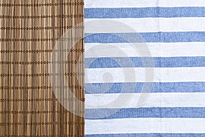 Brown bamboo mat on table cloth with blue stripe.