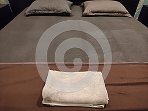 brown bed with pillows and towels prepared in hotel lodging room