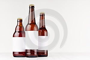 Brown beer bottles collection different type with blank white label on white wooden board, mock up.