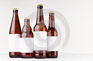 Brown beer bottles collection different type with blank white label on white wooden board, mock up.