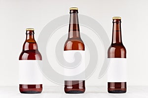 Brown beer bottles collection different type with blank white label on white wooden board, mock up.