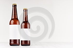 Brown beer bottles longneck 500ml and 330ml with blank white label on white wooden board, mock up.