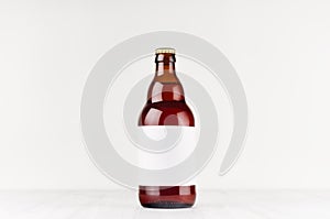 Brown belgian steinie beer bottle 500ml with blank white label on white wooden board, mock up.