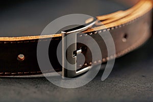 Brown belt made of genuine brown leather handmade on a dark background