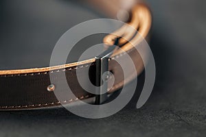 Brown belt made of genuine brown leather handmade on a dark background