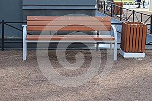 Brown bench and trash can near the house