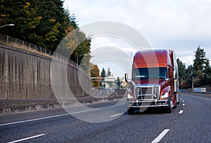 Brown big rig semi truck with grille guard running on the turning highway