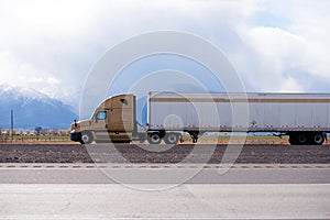 Brown big rig semi truck transporting cargo in refrigerator semi