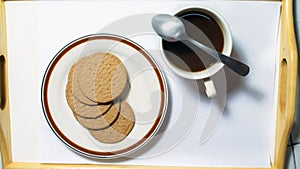 Brown biscuits in dish pairing with black coffee with teaspoon