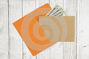 Brown blank greeting card with envelope with money on textured weathered whitewash wood background
