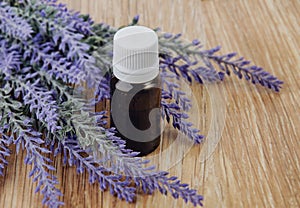 Organic essential oil in bottle and lavender flowers on wooden