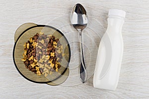 Brown bowl with breakfast cereals in form stars, spoon, yogurt