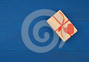 Brown box with a gift and a red paper heart tied to a rope