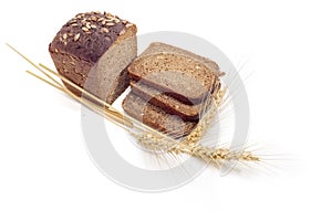 Brown bread with grain of sunflowers and wheat spikes