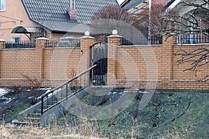 Brown brick fence wall with black metal door