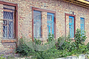 Brown brick wall of an old rural house with a row of windows
