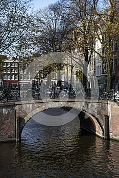 Brown bridge with bikes over the canal in autumn in Amsterdam