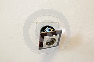 Brown broken electrical socket fell out of the wall. The socket is torn from the wall. A violation of electric safety,