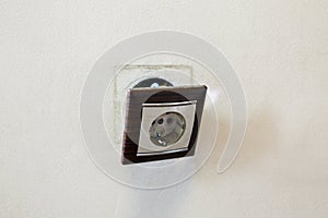 Brown broken electrical socket fell out of the wall. The socket is torn from the wall. A violation of electric safety,