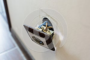 Brown broken electrical socket fell out of the wall. The socket is torn from the wall. A violation of electric safety,