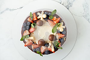 Brown cake Three chocolates decorated with blueberries, strawberries and chocolate drips on top. White background