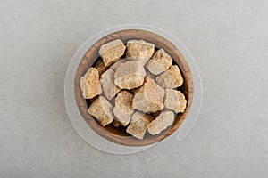 Brown cane sugar cubes in wooden bowl