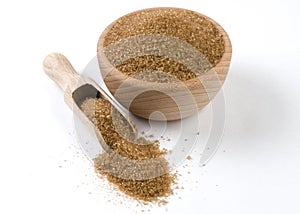Brown or cane sugar in wooden bowl and scoop isolated on white background. Spices and food ingredients