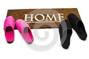 Brown carpet doormat with text Home and slippers.