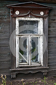 Brown carved platband cracked glass window of old traditional russian wooden house