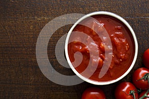 Brown ceramic bowl of chopped tinned tomatoes.