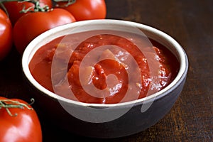 Brown ceramic bowl of chopped tinned tomatoes.