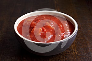 Brown ceramic bowl of chopped tinned tomatoes.