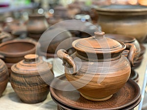 Brown ceramic dishes in a shop window. Clay pots, plates and handmade cups