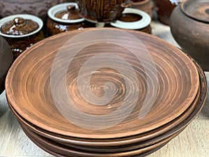 Brown ceramic dishes in a shop window. Clay pots, plates and handmade cups