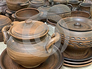 Brown ceramic dishes in a shop window. Clay pots, plates and handmade cups