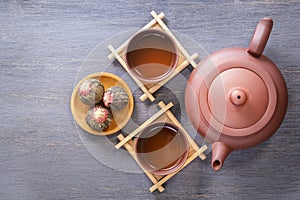 Brown ceramic teapot with cups on special wooden coasters is prepared for a traditional Asian tea ceremony. View from above.