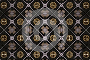 Brown checkered pattern of crosses and round shapes on a black background.