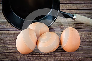 Brown chicken egg and iron pan on the table.