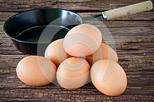 Brown chicken egg and iron pan on the table.