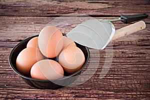 Brown chicken egg and iron pan on the table.