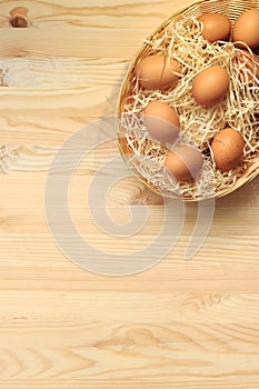 Brown chicken eggs in a basket on a wooden table