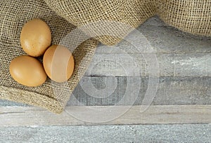 Brown chicken eggs on burlap over wooden background