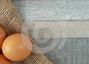 Brown chicken eggs on burlap over wooden background