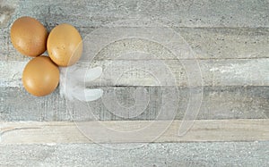 Brown chicken eggs with feather at wooden background