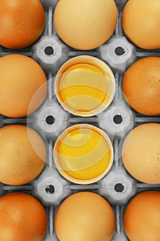 Brown chicken eggs package box with 2 opened and visible egg yolks
