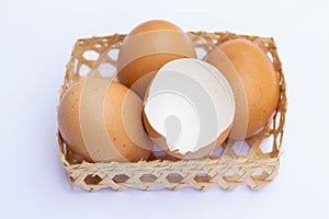 Brown chicken eggs are placed in bamboo trays. With an eggshell on a white background