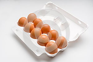 Brown chicken eggs in a plastic package on a white background