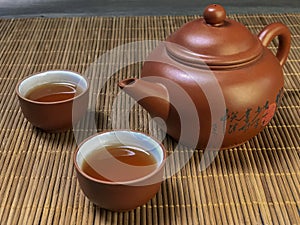 Brown chinese tea set of a teapot and cups on bamboo table mat .