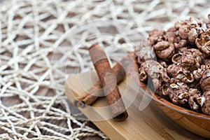 Brown chocolate flawored popcorn on the wood plate with cinnamon